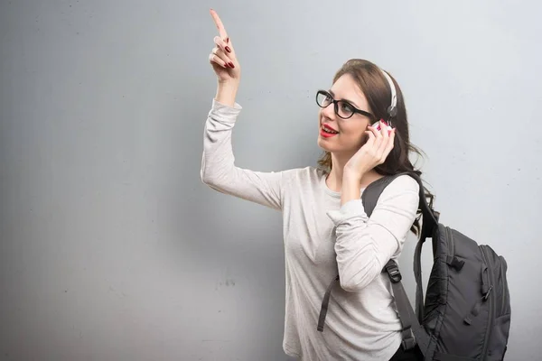 Student vrouw luisteren muziek op gestructureerde achtergrond — Stockfoto