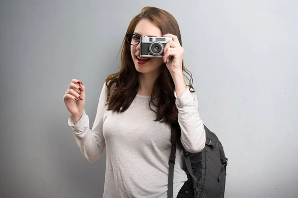 Studentka žena držící fotoaparát na podklad s texturou — Stock fotografie