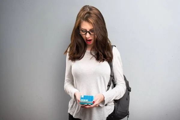 Bir hesap makinesi dokulu arka plan üzerinde tutan öğrenci kadın — Stok fotoğraf