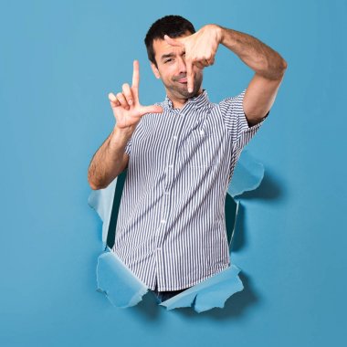 Yakışıklı adam bir kağıt delikten parmaklarıyla odaklanarak