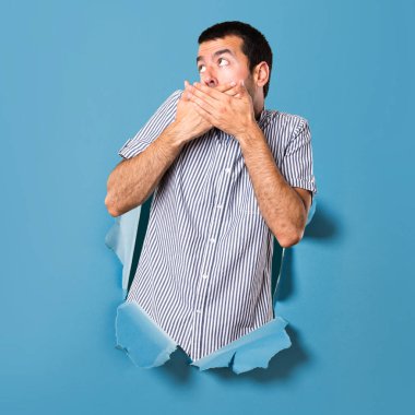 Yakışıklı adam yapma sürpriz jest bir kağıt delikten