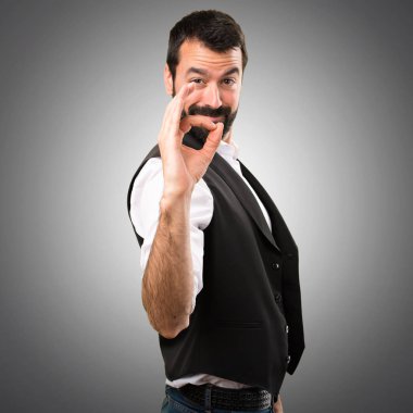 Serin adam gri arka plan üzerinde oturum Tamam yapma