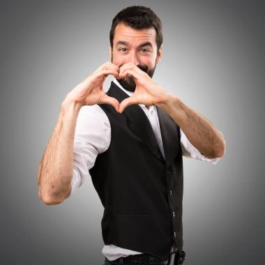 Cool adam gri arka plan üzerinde elleriyle bir kalp yapma