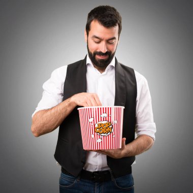 Serin adam yeme popcorns gri arka plan üzerinde