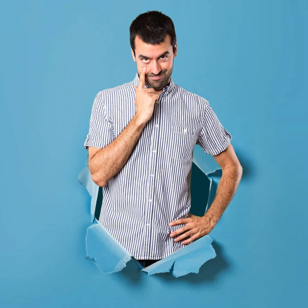 Hombre guapo mostrando algo a través de un agujero de papel —  Fotos de Stock