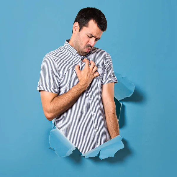 Homem bonito com dor no coração através de um buraco de papel — Fotografia de Stock