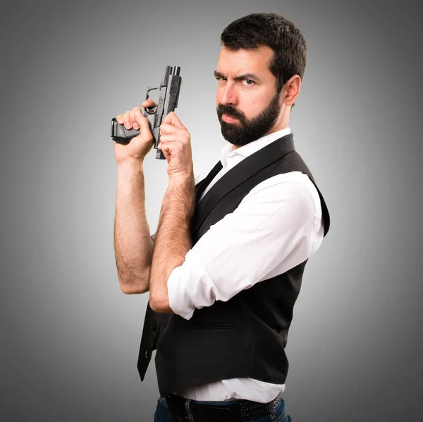 Cool man holding a pistol on grey background