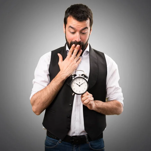 Hombre fresco sosteniendo reloj vintage sobre fondo gris — Foto de Stock