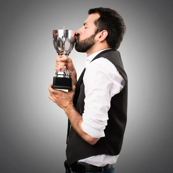 Крутой парень держит трофей на сером фоне — стоковое фото