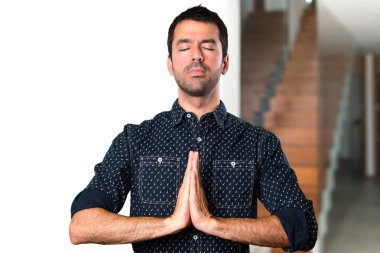 Evin içinde zen pozisyonundaki esmer adam