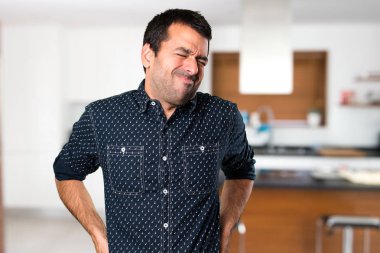 Esmer adam evin içinde sırt ağrısı ile