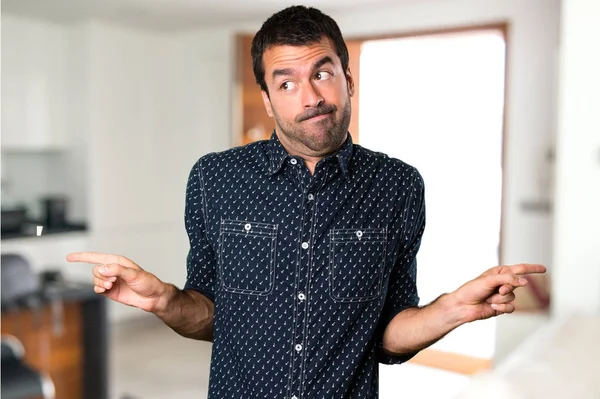 Brunette mies osoittaa laterals ottaa epäilyksiä sisällä talossa — kuvapankkivalokuva
