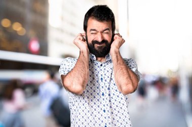 Kulakları kapsayan sakallı yakışıklı esmer adam