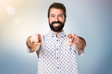 Öne doğru işaret eden sakallı yakışıklı esmer adam