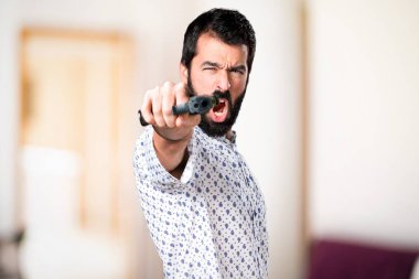 Bir tabanca tutan sakallı yakışıklı esmer adam