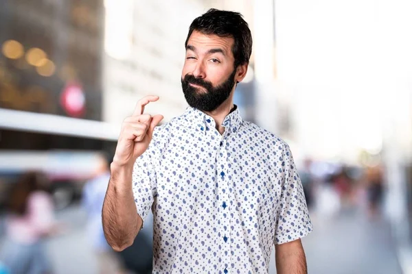 Красивый брюнетка мужчина с бородой делает крошечный знак — стоковое фото