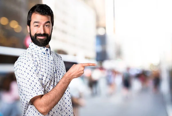 Knappe brunette man met baard wijzend naar de laterale — Stockfoto