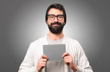 Boş bir afişini gri arka plan üzerinde tutarak hipster adam