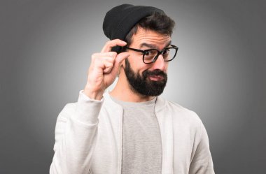 Küçük yapma hipster adam gri arka plan üzerinde oturum