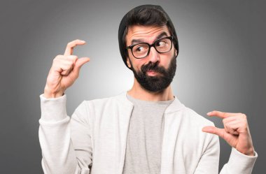 Küçük yapma hipster adam gri arka plan üzerinde oturum
