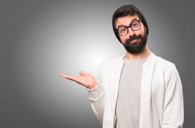 Bir şey gri arka plan üzerinde tutan hipster adam