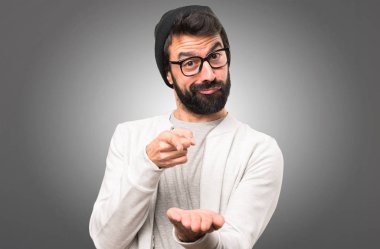 Bir şey gri arka plan üzerinde tutan hipster adam