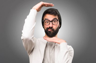 Hipster adam yüzünü gri arka plan üzerinde duruluyor