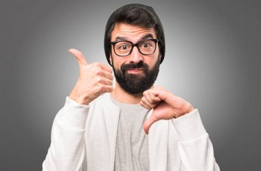 İyi-kötü işareti gri arka plan üzerinde yapma hipster adam