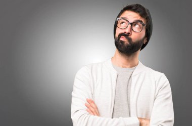 Hipster adam gri arka plan üzerinde düşünme