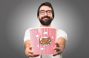 Mutlu Hipster adam yeme popcorns gri arka plan üzerinde