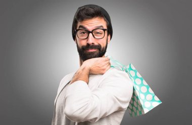 Hipster adam gri arka plan üzerinde alışveriş çantası ile