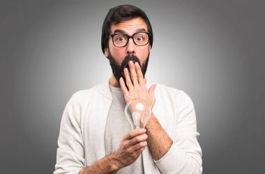 Bir ampul gri arka plan üzerinde tutarak şaşırmış Hipster adam