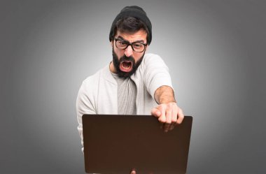 Hipster adam gri arka plan üzerinde dizüstü bilgisayar ile