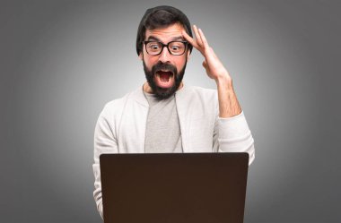 Şaşırmış Hipster adam gri arka plan üzerinde dizüstü bilgisayar ile