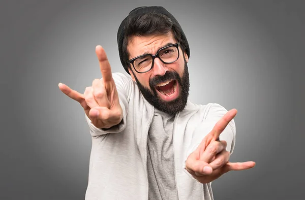 Hipster man maken rock gebaar op grijze achtergrond — Stockfoto