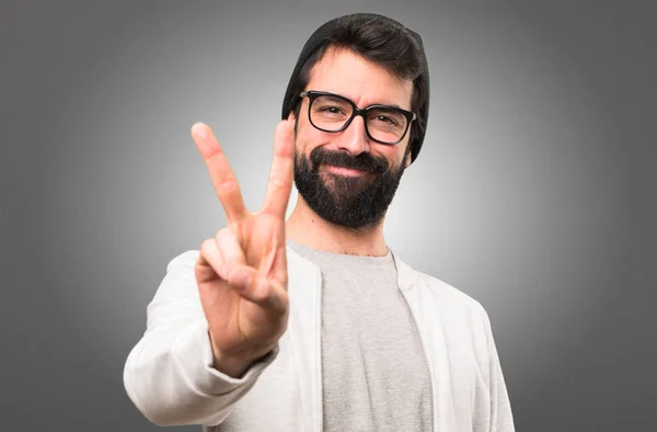 Hipster uomo contando due su sfondo grigio — Foto Stock