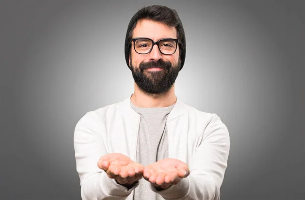 Hipster hombre sosteniendo algo sobre fondo gris —  Fotos de Stock