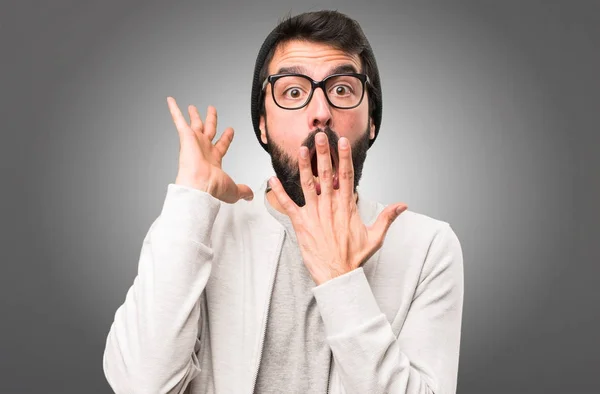 Hipster-Mann macht Überraschungsgeste auf grauem Hintergrund — Stockfoto