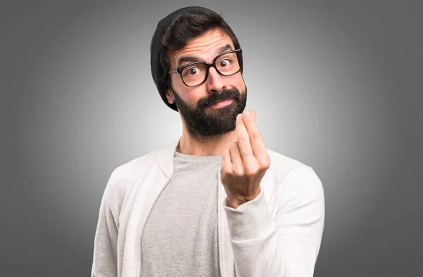 Hipster hombre haciendo dinero gesto sobre fondo gris —  Fotos de Stock