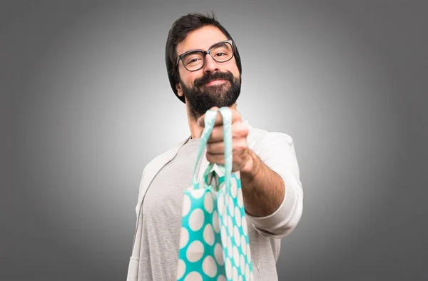 Šťastný muž Hipster s nákupní taškou na šedém pozadí — Stock fotografie