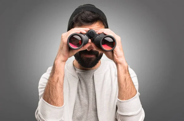 Hipster homem com binóculos em fundo cinza — Fotografia de Stock