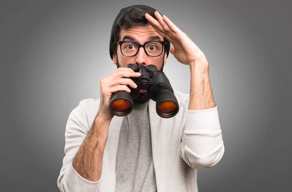Hipster uomo con binocolo su sfondo grigio — Foto Stock