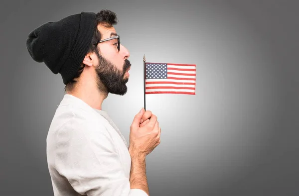 灰色の背景にアメリカの国旗を保持している流行に敏感な男 — ストック写真