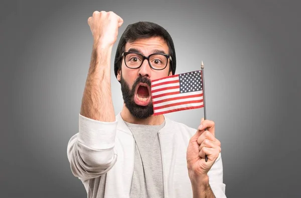 Feliz hombre Hipster sosteniendo una bandera americana sobre fondo gris —  Fotos de Stock