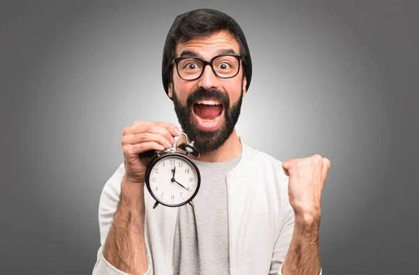 Lycklig Hipster man håller vintage klocka på grå bakgrund — Stockfoto