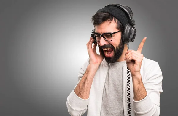 Feliz Hipster homem ouvindo música em fundo cinza — Fotografia de Stock