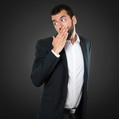 Yakışıklı işadamı ağzını siyah arka plan üzerine kaplama