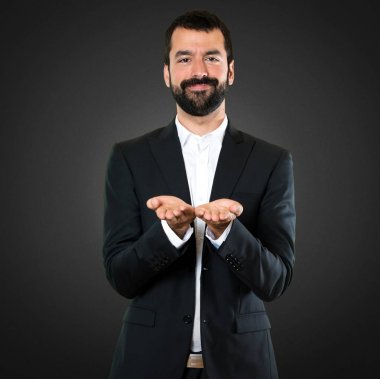 Yakışıklı işadamı bir şey siyah arka planda tutan
