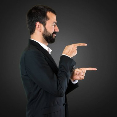 Yakışıklı işadamı lateral siyah arka plan üzerine işaret
