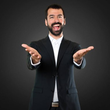 Yakışıklı işadamı siyah arka plan üzerine bir şey sunmak